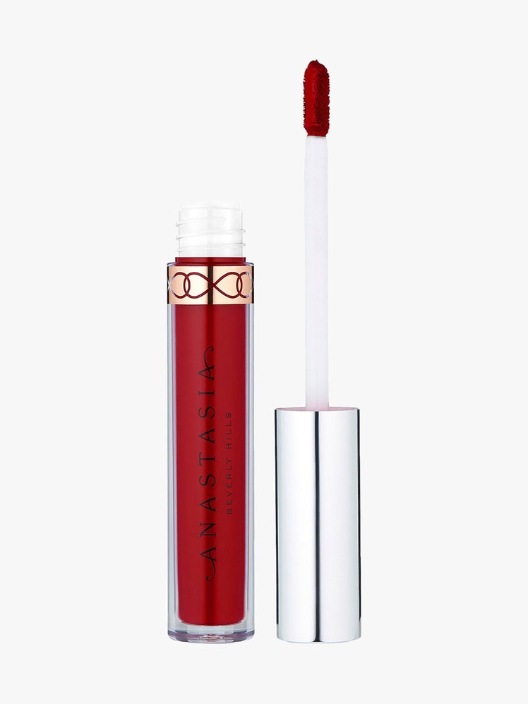 ABH Liquid Lipstick in American Doll vial of red liquid lipstick with silver cap and wand to the side on light gray...