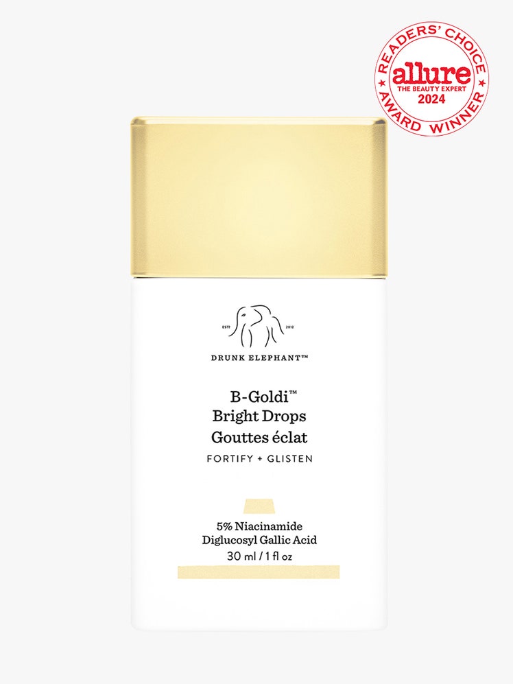 Drunk Elephant BGoldi Bright Drops white rectangle bottle with gold cap on light gray background with white and red...