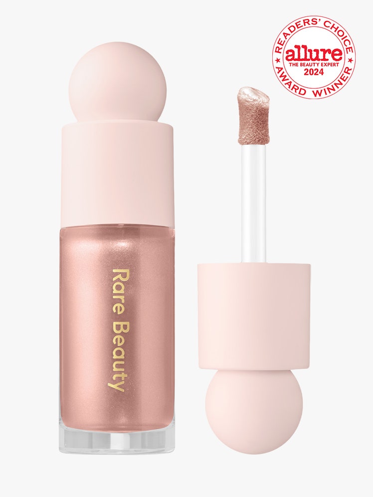 Rare Beauty Positive Light Liquid Luminizer vial of shimmery pink liquid highlighter with light pink bauble cap on light...