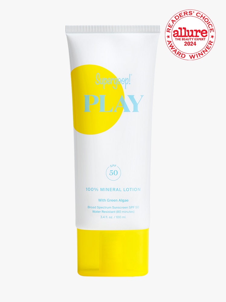 Supergoop Play 100% Mineral Lotion SPF 30 white tube with yellow dot on it and cap on light gray background with white and red Allure Readers' Choice Award seal in the top right corner