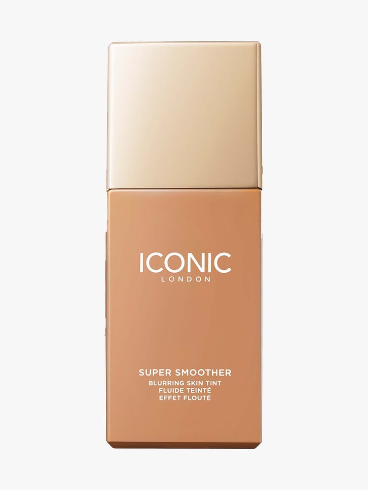 Iconic London Super Smoother Blurring Skin Tint rectangle bottle of skin tint with gold cap on light gray background